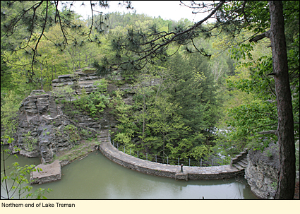 Northern end of Lake Treman in Buttermilk Falls State Park in Ithaca, New York, USA, showing stone dam and walkway.