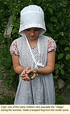 A girl, one of the many children who populate the "village" during the summer, holds a leopard frog from the center pond.