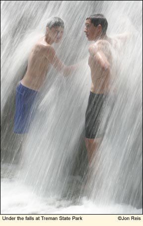 Boys standing under the falls at Treman State Park in the Finger Lakes, New York USA. Photo by Jon Reis.