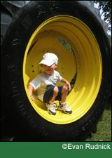 A young boy inspecting a big tire in the Finger Lakes, New York