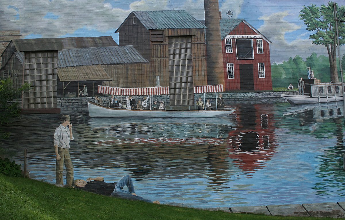A mural of the Erie Canal on a building in Port Byron, New York. The mural is by Dawn Jordan and is titled "Summer Afternoon on the Erie Canal." 