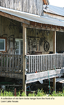 A collection of old farm tools hangs from the front of a Loon Lake house.