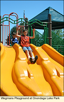 Children at a slide in Wegmans Playground at Onondaga Lake Park on Onondaga Lake in the Finger Lakes, New York USA.