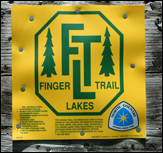 Sign on a tree in the Finger Lakes, New York, identifying the trail as part of the Finger Lakes Trail System.