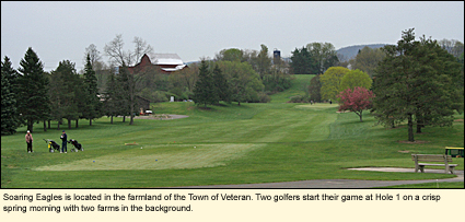 Soaring Eagles is located in the farmland of the Town of Veteran. Two golfers start their game at Hole 1 on a crisp spring morning with two farms in the background.