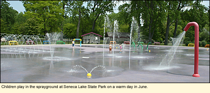 Children play in the sprayground at Seneca lake State park on a warm day in June.