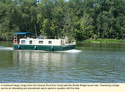 A chartered barge chugs down the Seneca River/Erie Canal past the Bonita Bridge launch site. Chartering a barge can be an interesting and educational way to send a vacation with the kids.